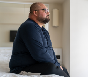 obese veteran sitting on his bed